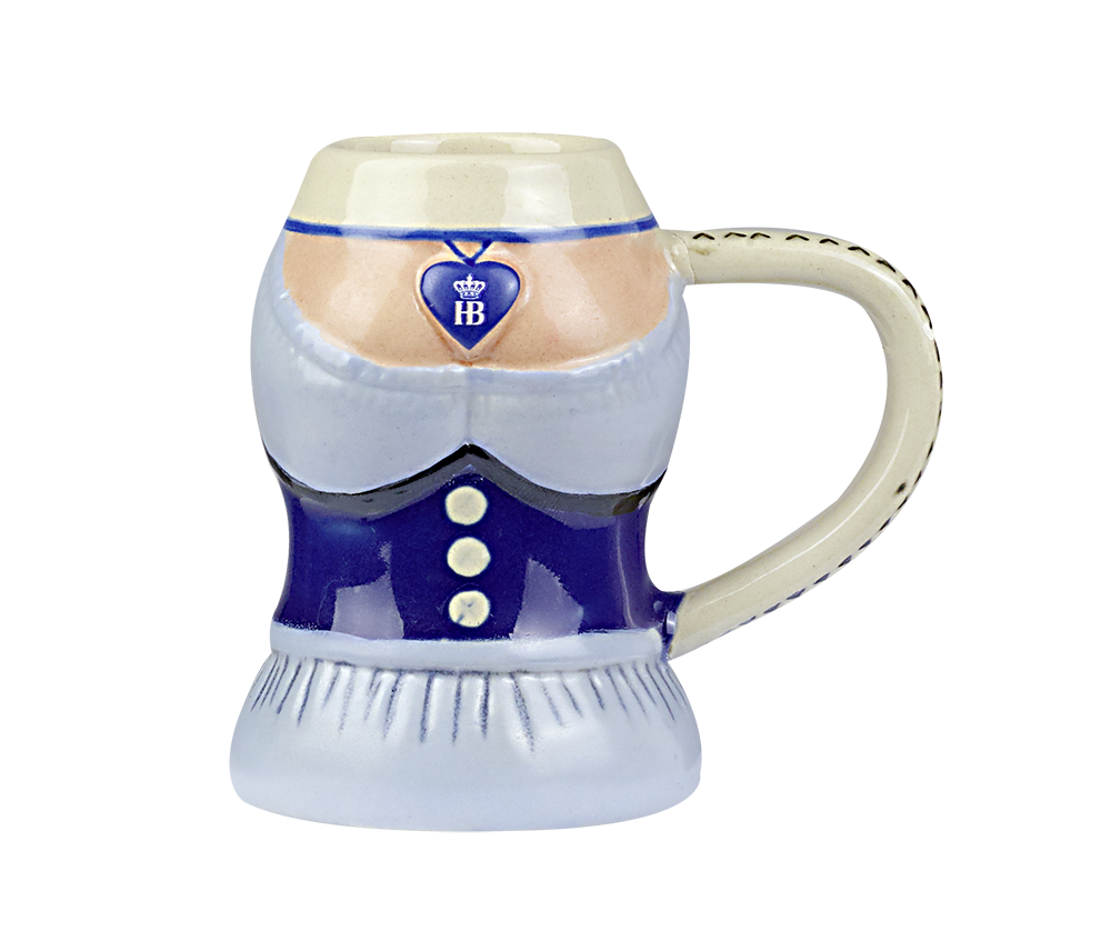 Steingut-Schnapsglas in Form eines Dirndls gestaltet. Das Glas ist bunt bemalt und zeigt ein blaues Mieder mit Knöpfen, eine weiße Bluse und ein Dekolleté. Um den Hals ist ein Herzanhänger mit dem blauen HB-Logo (Hofbräuhaus) und einer Krone zu sehen. Sei