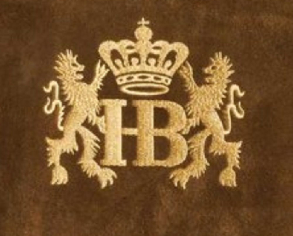 Goldenes Hofbräuhaus-Logo auf braunem Leder: Krone über den Buchstaben HB, flankiert von zwei stehenden Löwen