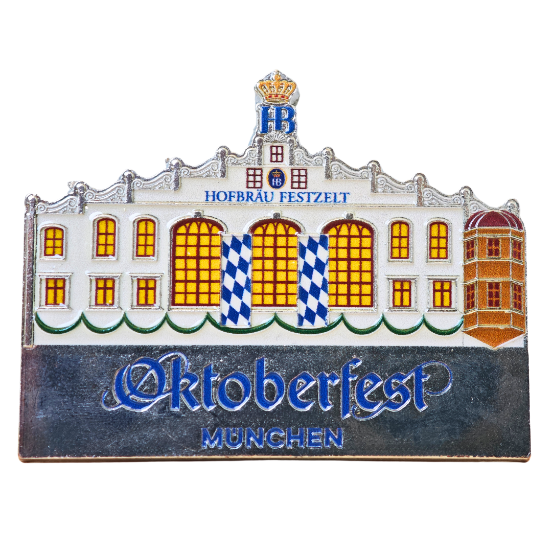 „Magnet mit Illustration eines Festzelts im bayerischen Stil, blau-weiß kariertes Eingangsdesign, darunter Schriftzug ‚Oktoberfest München‘.“